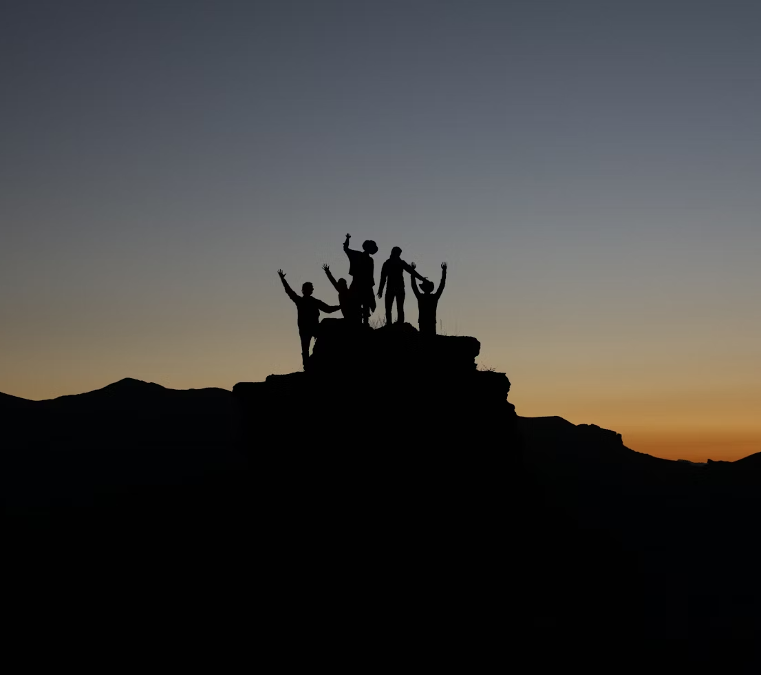 silhouettes of a team of people standing before a sunset